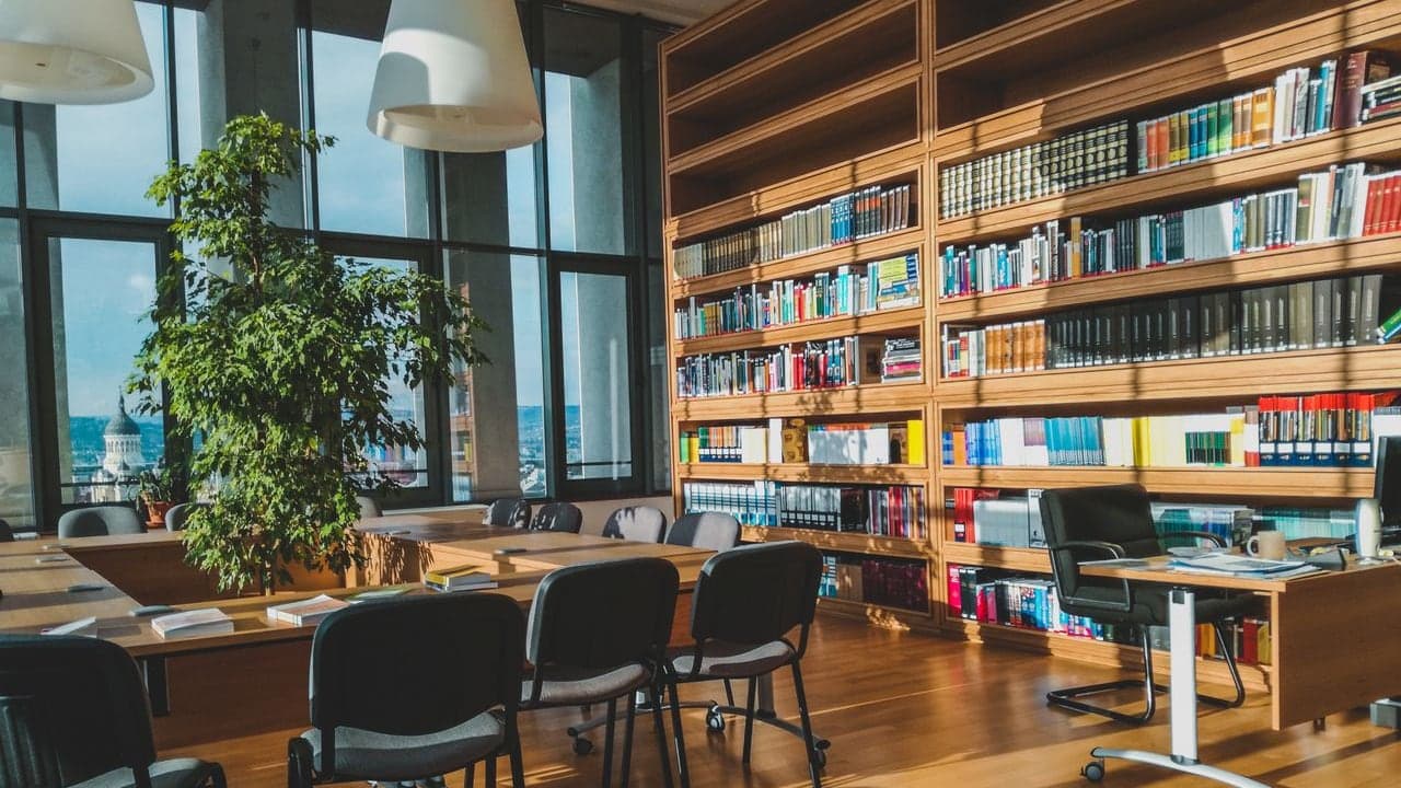Biblioteca jurídica luminosa y moderna con estanterías de libros, que evoca normas y gobernanza
