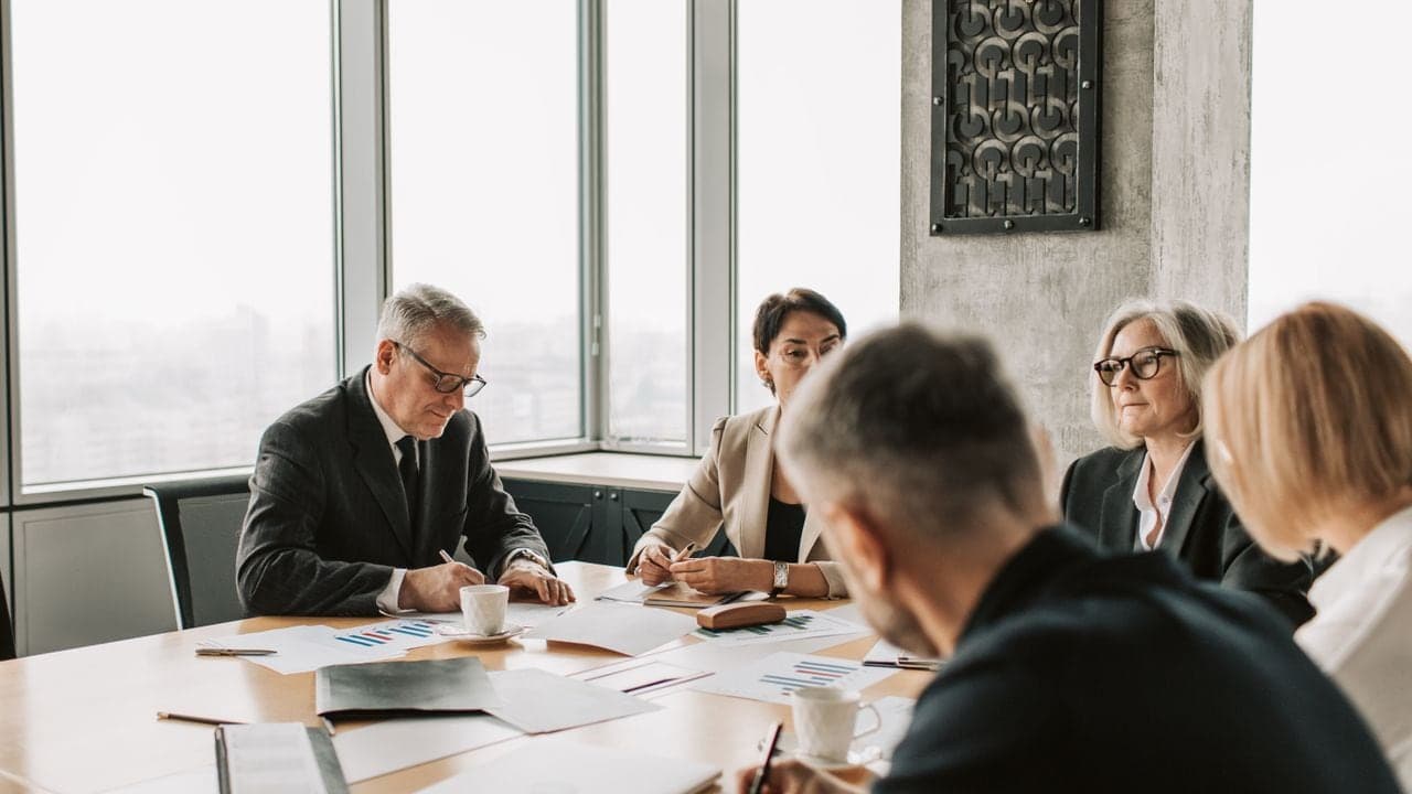 Ejecutivos en una sala de consejo revisando gráficos e informes