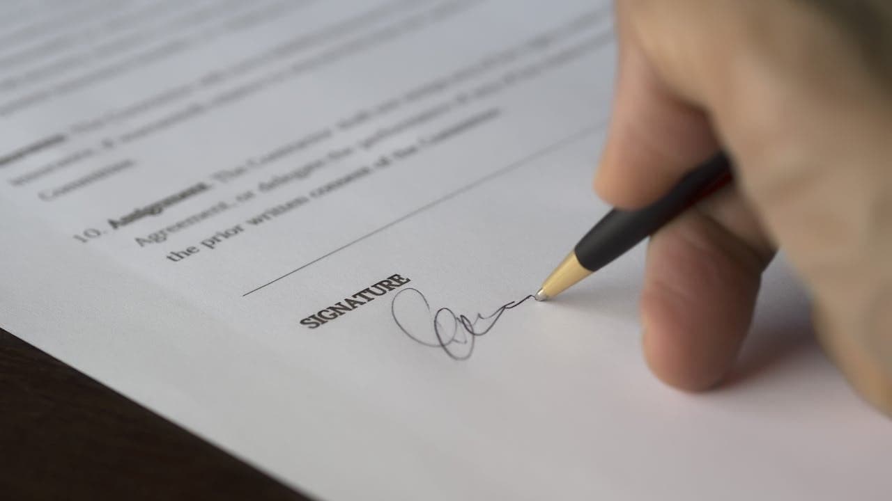 Mano firmando un documento de póliza con bolígrafo